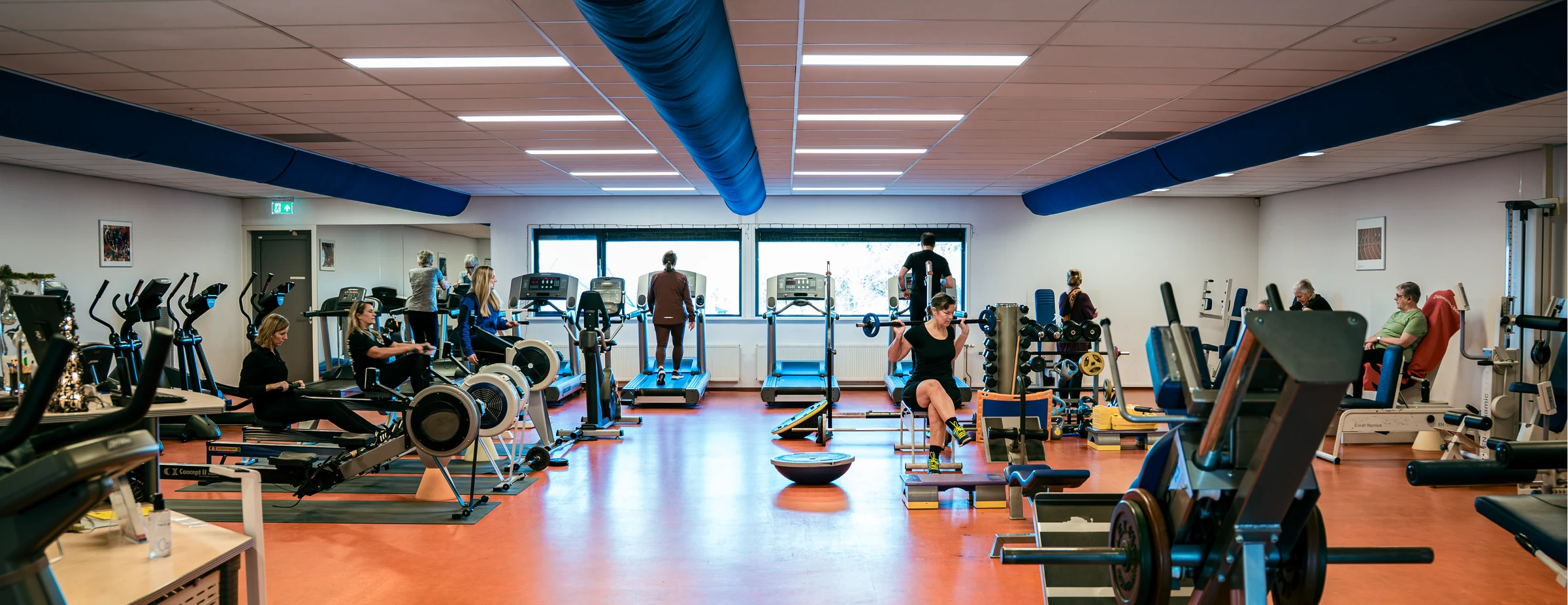 De ruime trainingszaal met cardio- en krachtapparatuur